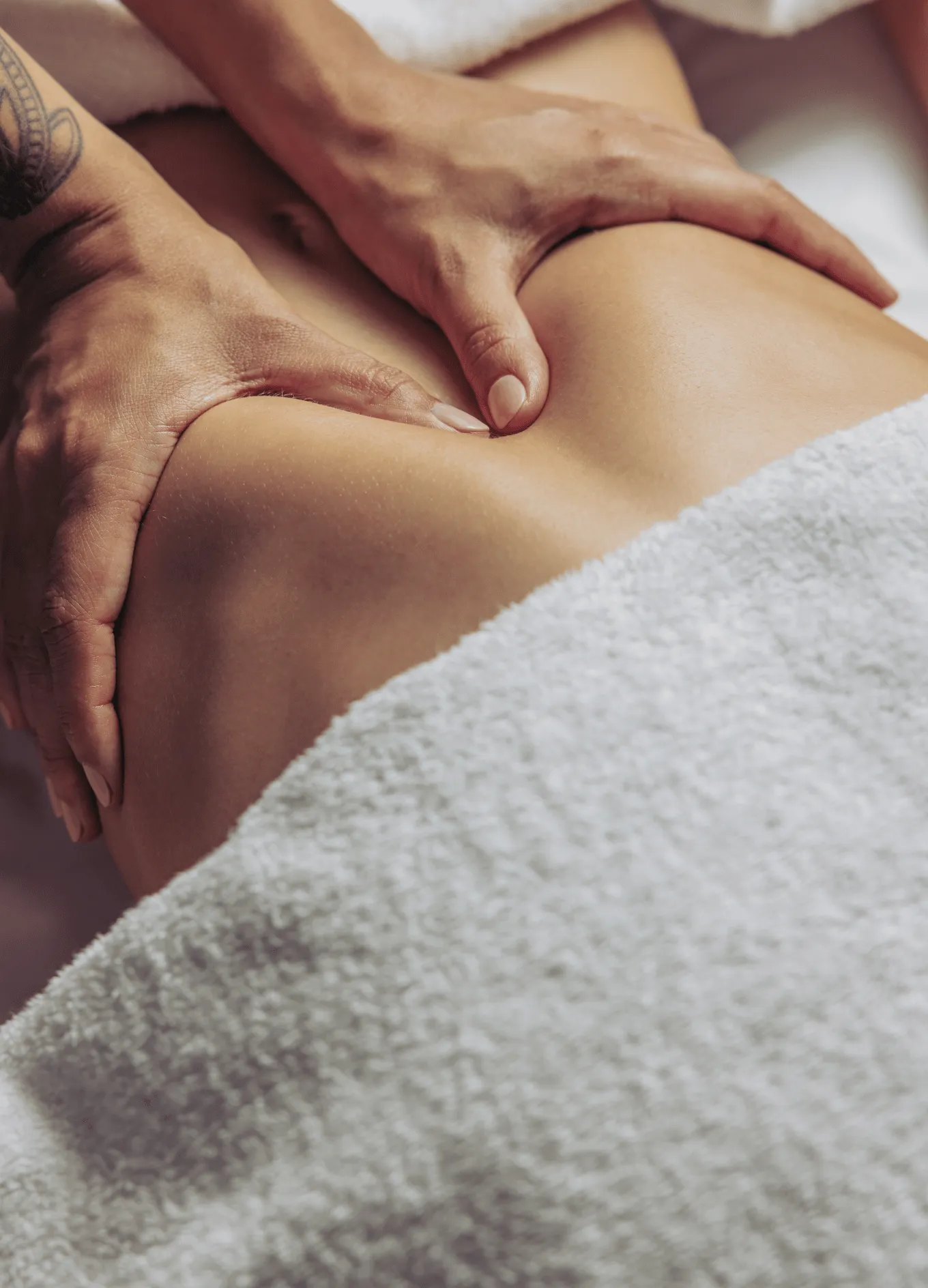 Close-up of hands giving a back massage on a person covered with a white towel.