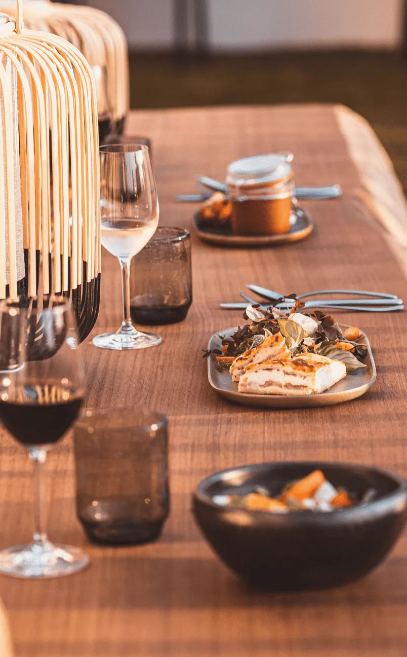 Wooden table set with plates of food, wine glasses, and decorative lanterns.