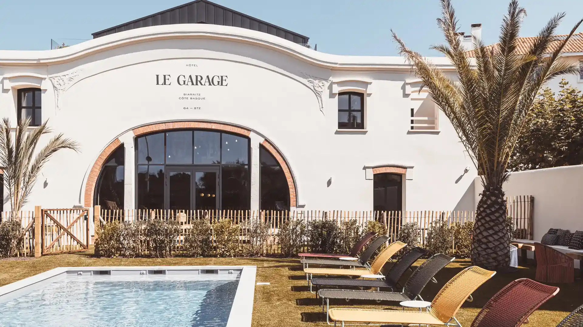 Swimming pool area and palm tree in front of the elegant architecture of Hotel Le Garage, Biarritz, Basque Coast.