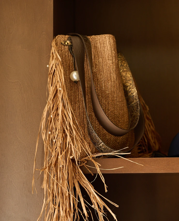 Stylish straw handbag with pearl embellishments displayed on a shelf in the boutique at Hôtel Régina Experimental, Biarritz.