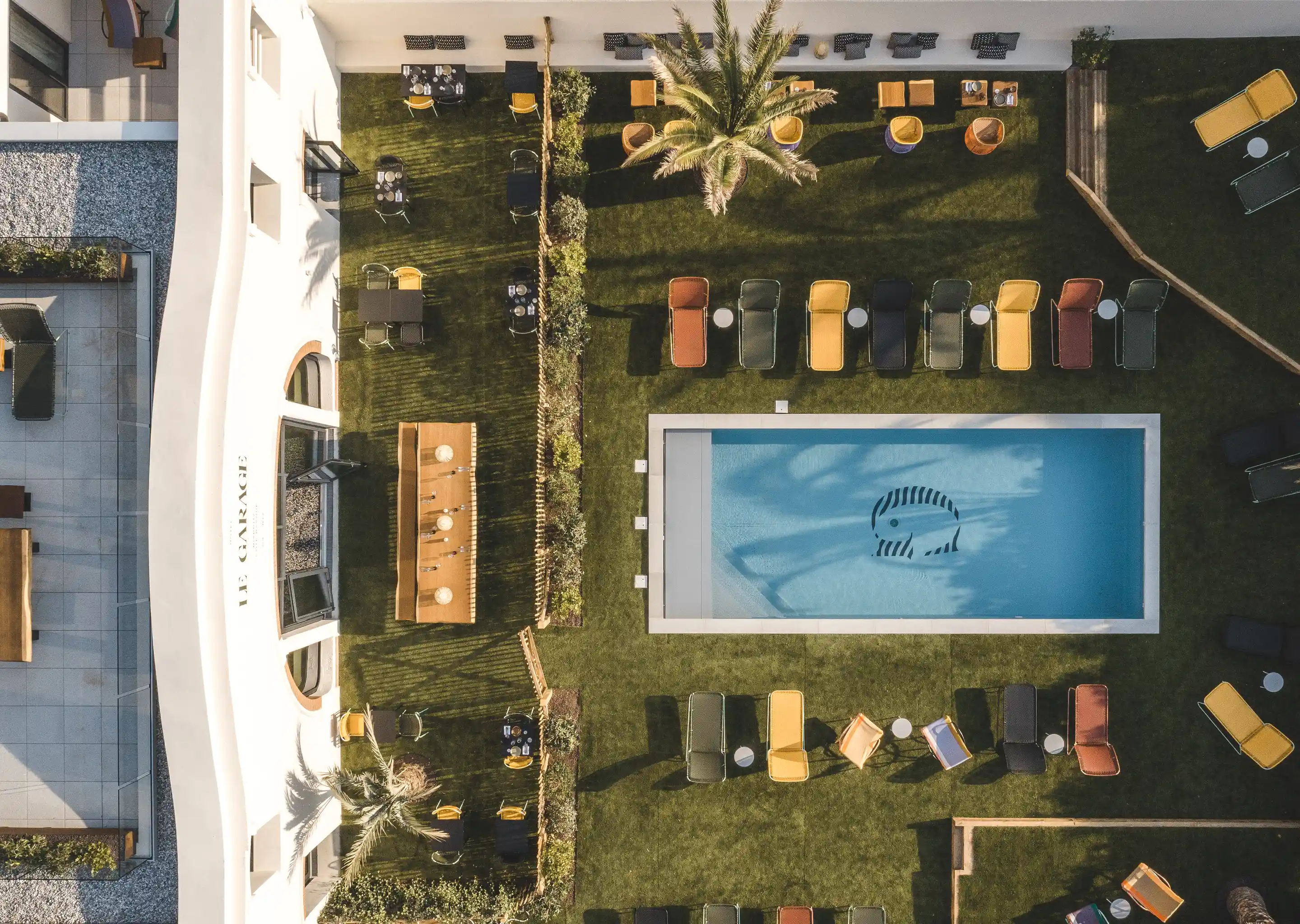 Overhead perspective of the outdoor dining area and pool deck at Hôtel Régina Experimental in Biarritz.