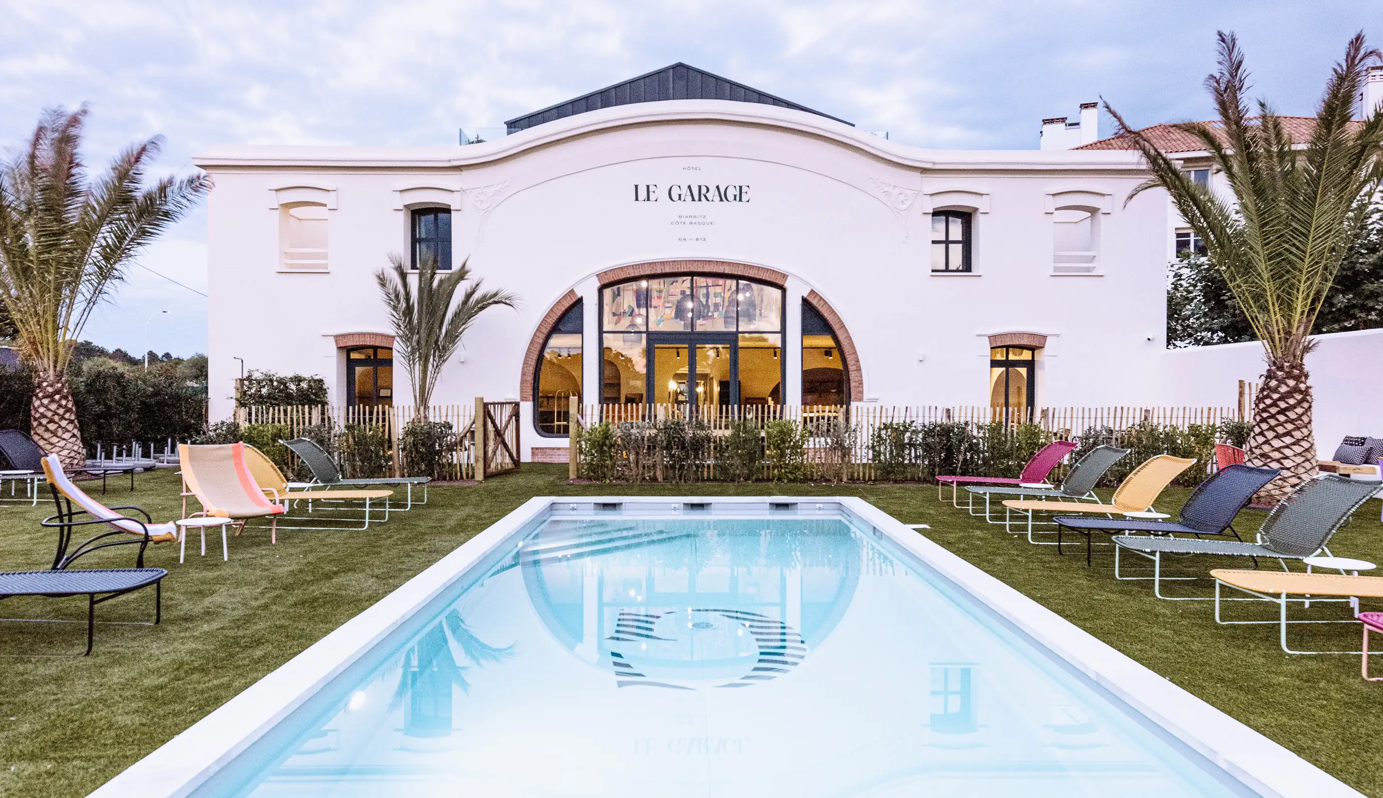 Facade of the Le Garage hotel in Biarritz with its outdoor swimming pool and manicured garden.