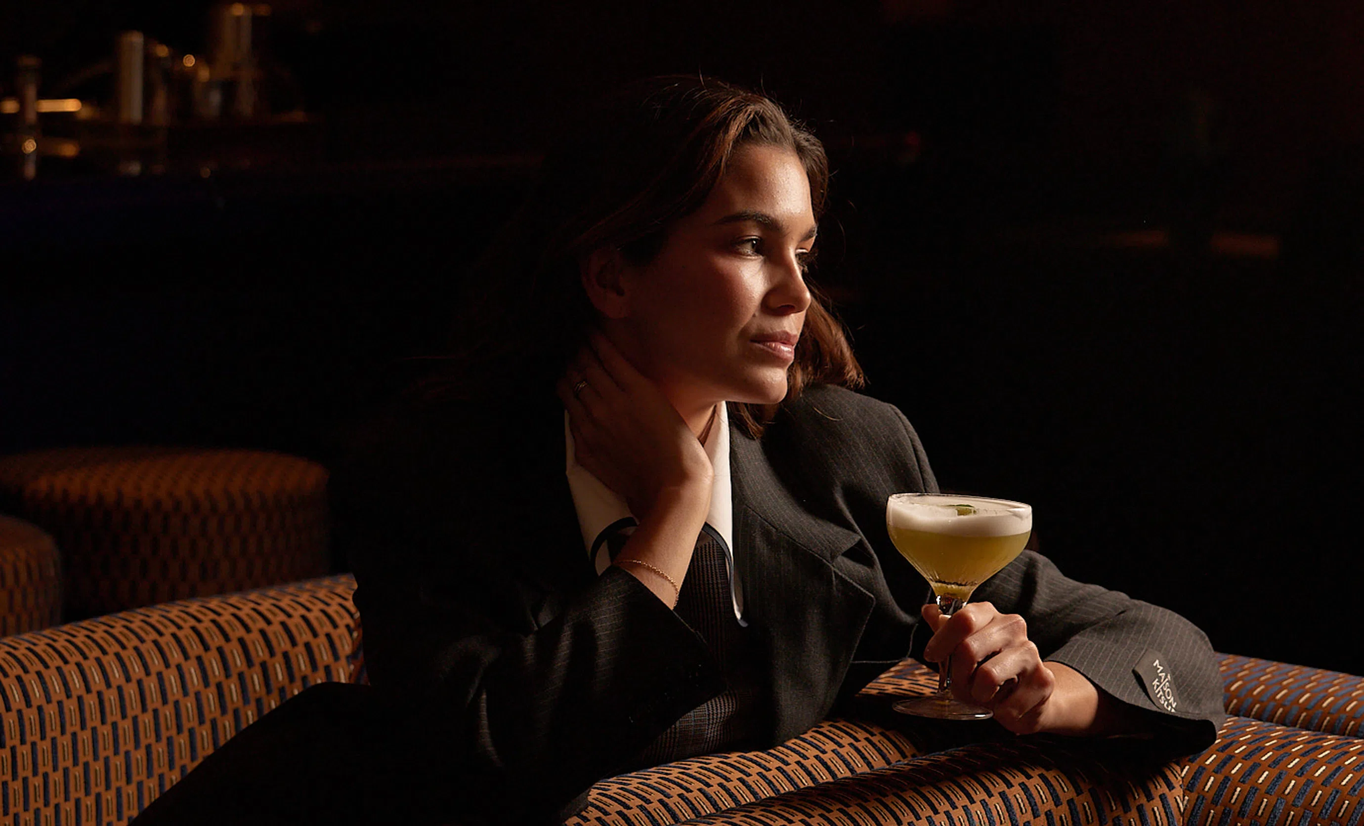 Portrait of a relaxed woman with a cocktail in hand, sitting in the designer lounge of the Experimental Cocktail Club.