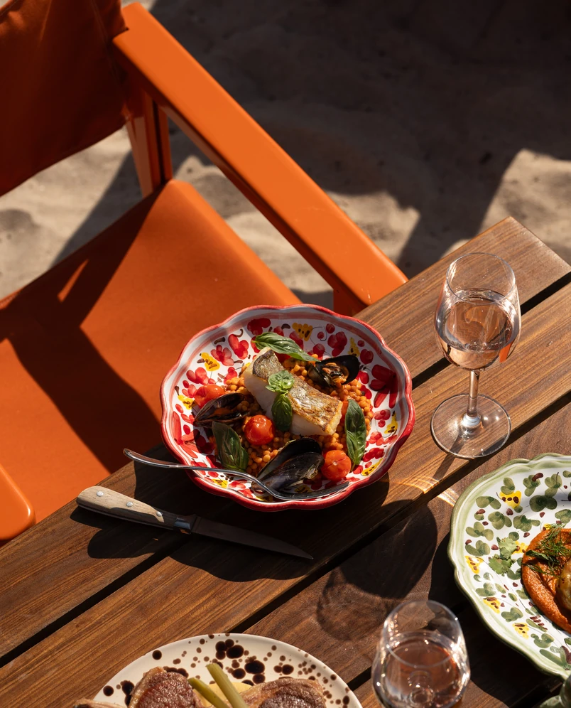 Gourmet fish and mussel dish with basil served on a decorative plate at an Experimental Group beach restaurant.