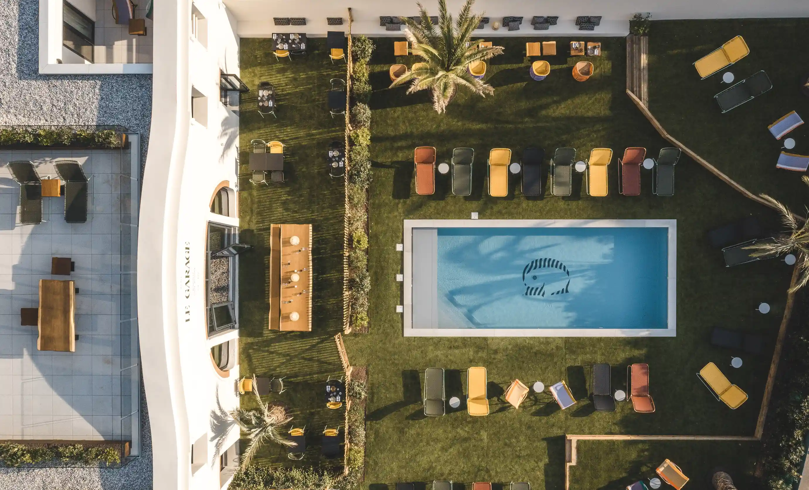 Top-down perspective of the Le Garage outdoor leisure area with pool and garden at an Experimental Group hotel.