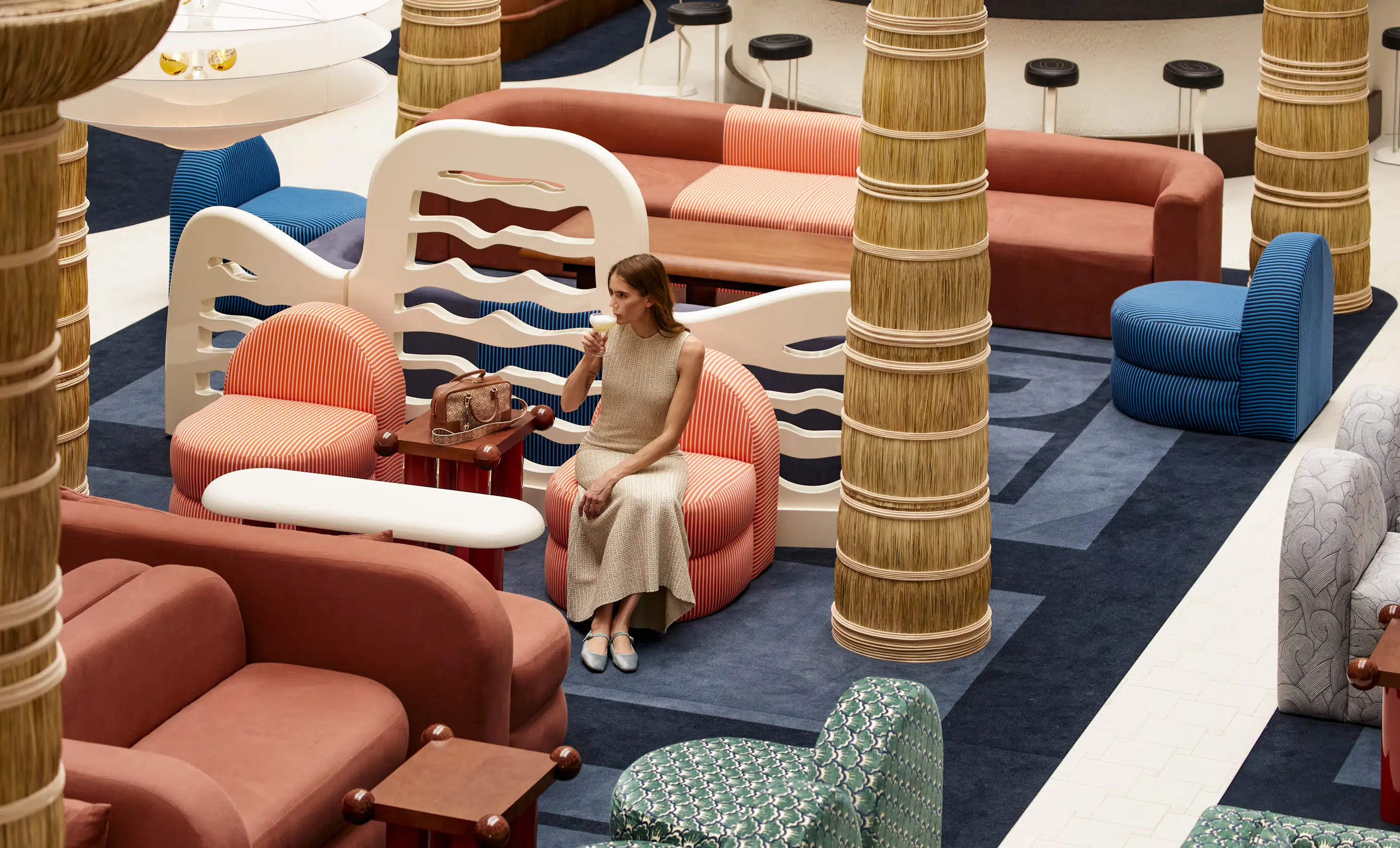 Elegant guest enjoying a cocktail in a designer lobby lounge featuring curated furniture by Experimental Group hotel.