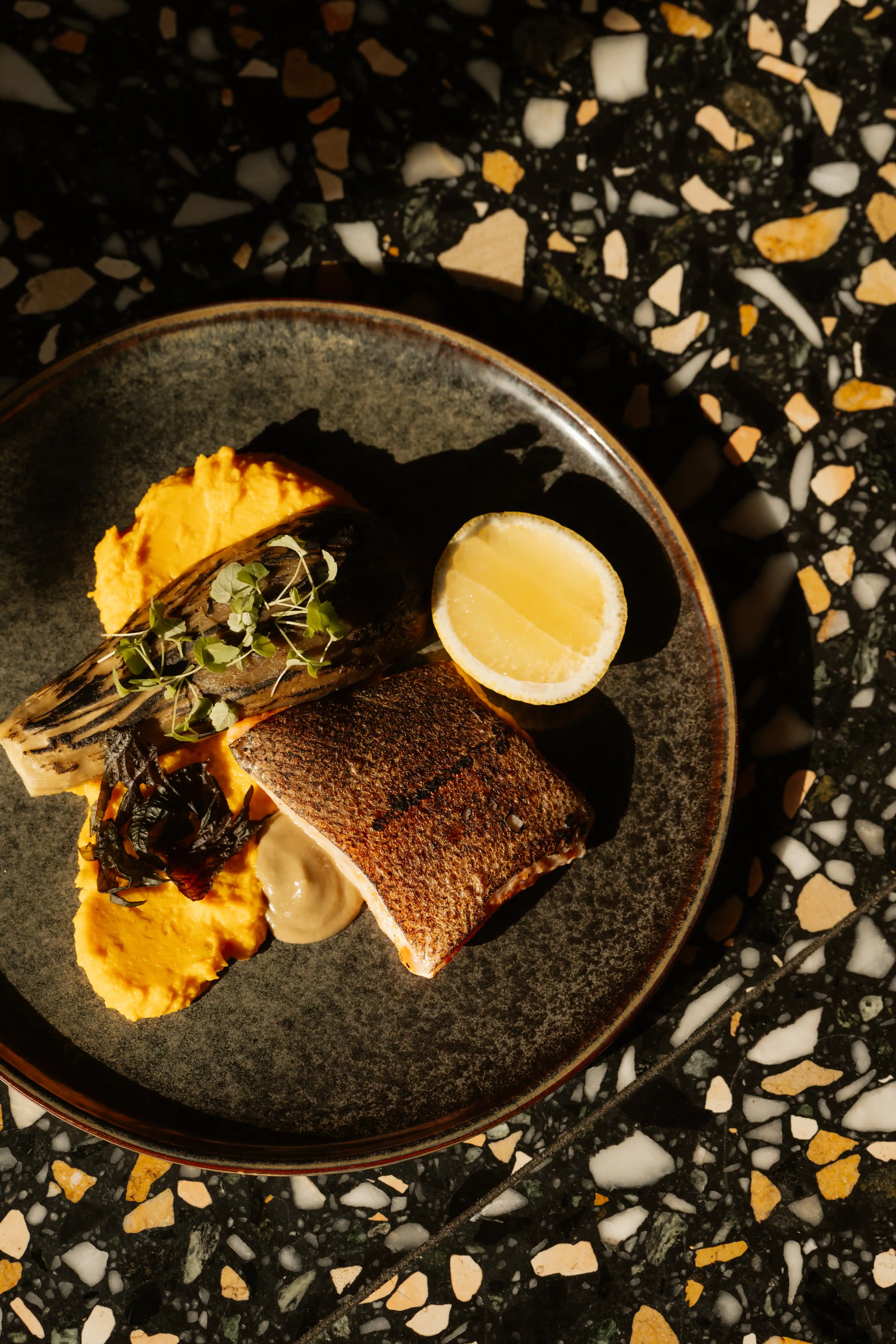 Grilled fish fillet served with puree and lemon, the refined culinary art of Experimental Group.