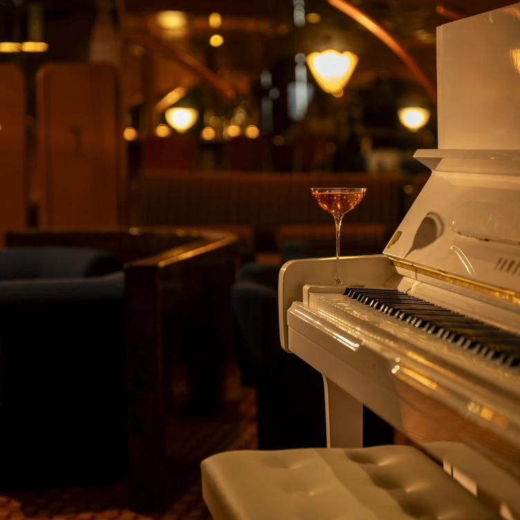 Focus on a cocktail glass placed on a white piano in an Experimental Group lounge area.