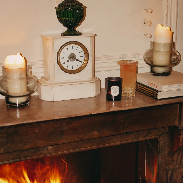 Zoom on the decoration of a marble fireplace with candles and a clock at La Compagnie des Vins Surnaturels, London.