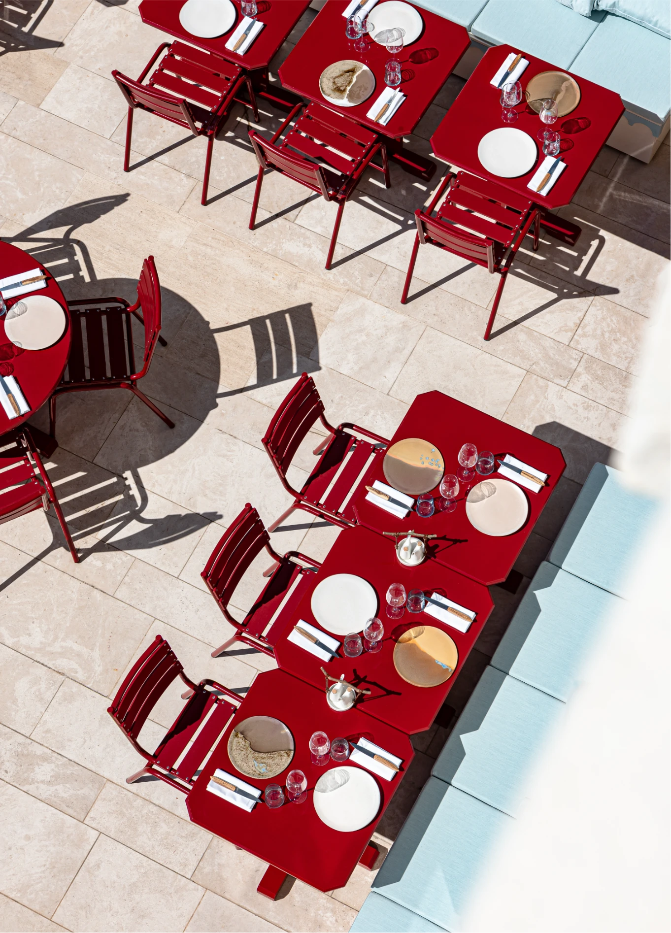 Overhead view of a dining room at Regina Experimental, highlighting the symmetrical layout of tables set with red chairs.