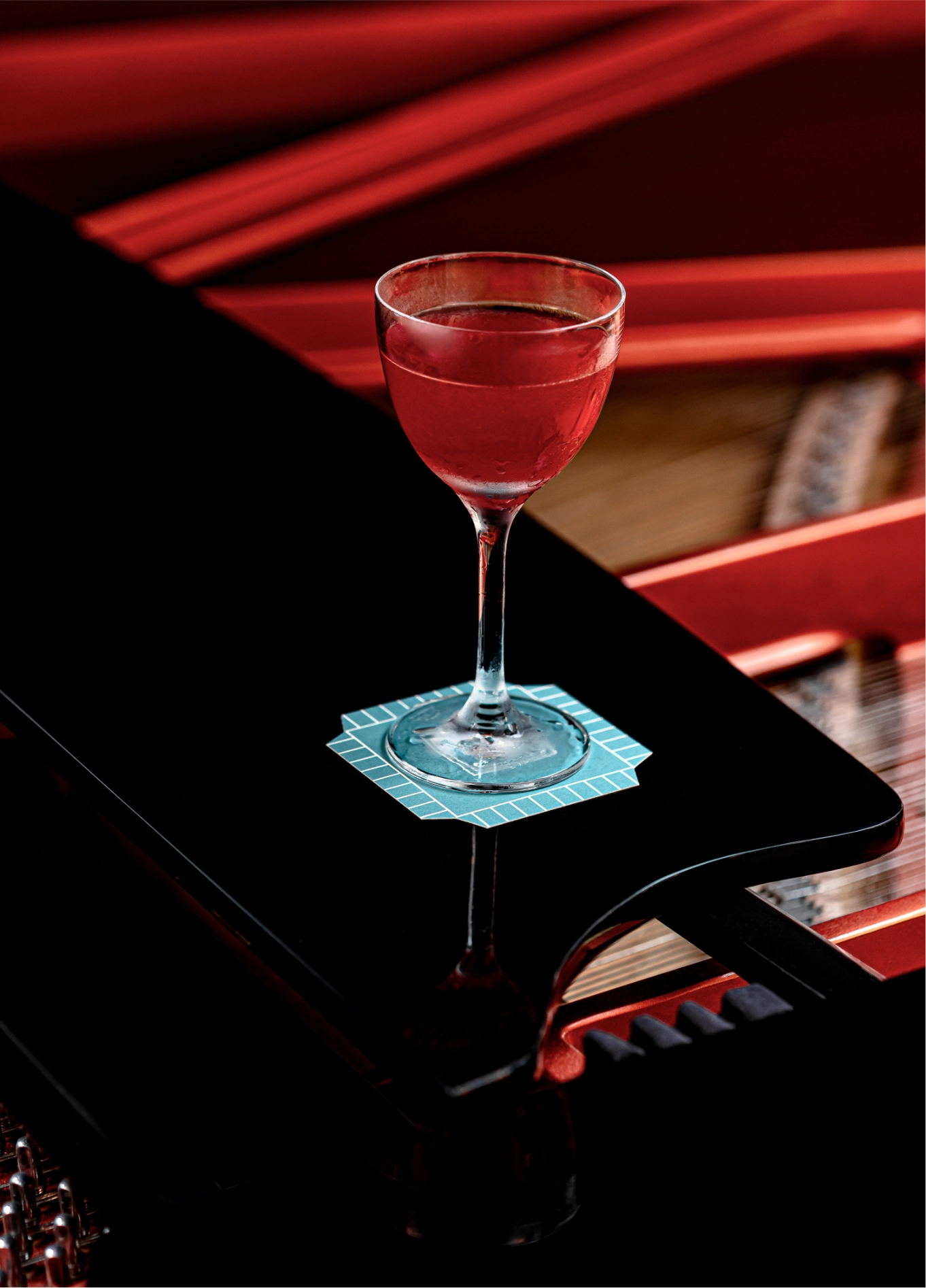A colorful cocktail glass placed on an elegant black piano at the Regina Experimental.