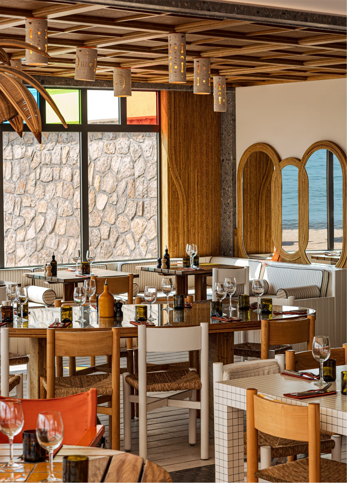 Bright and elegant restaurant dining room with natural stone decor and wooden ceiling beams, at an Experimental Group property.