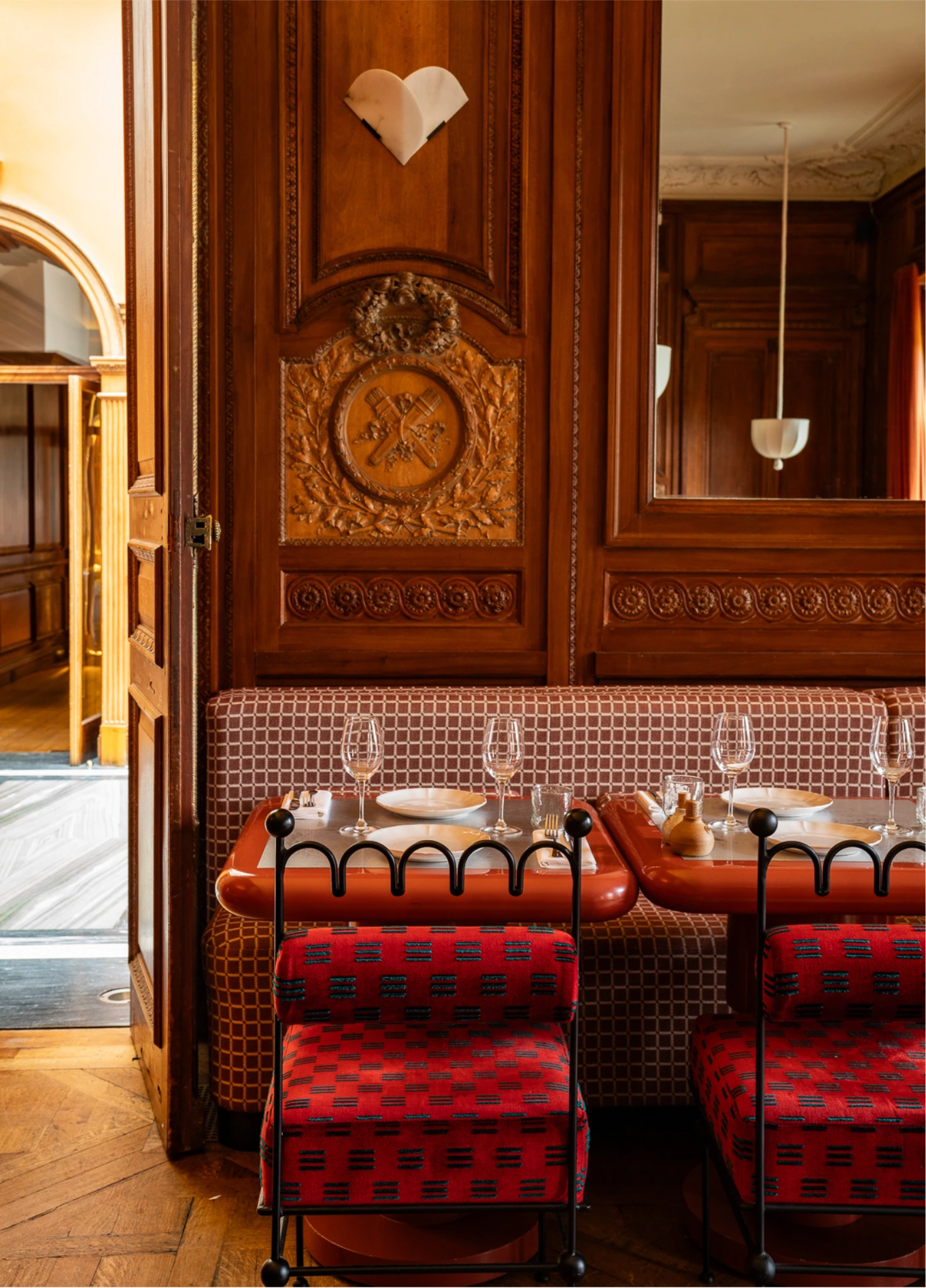 Elegant dining room with wooden panelling and red chairs at Cowley Manor restaurant, Cotswolds