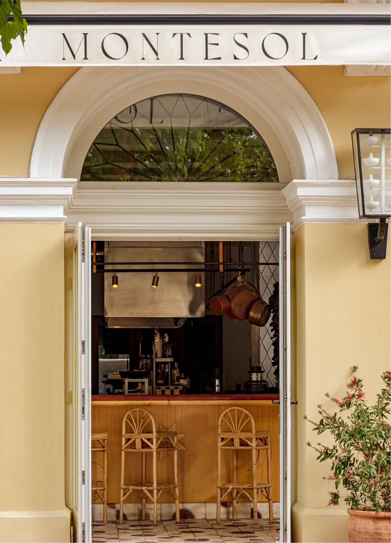 The entrance to the Montesol hotel with signage above an arched doorway leading to a bar, featuring potted plants.