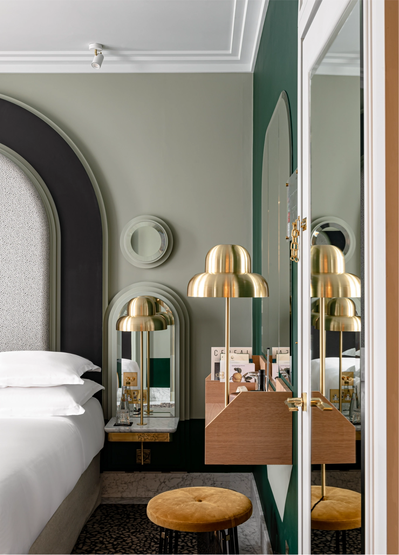 Bedroom with dark green headboard and golden mirrors at Henrietta Experimental, Covent Garden, London