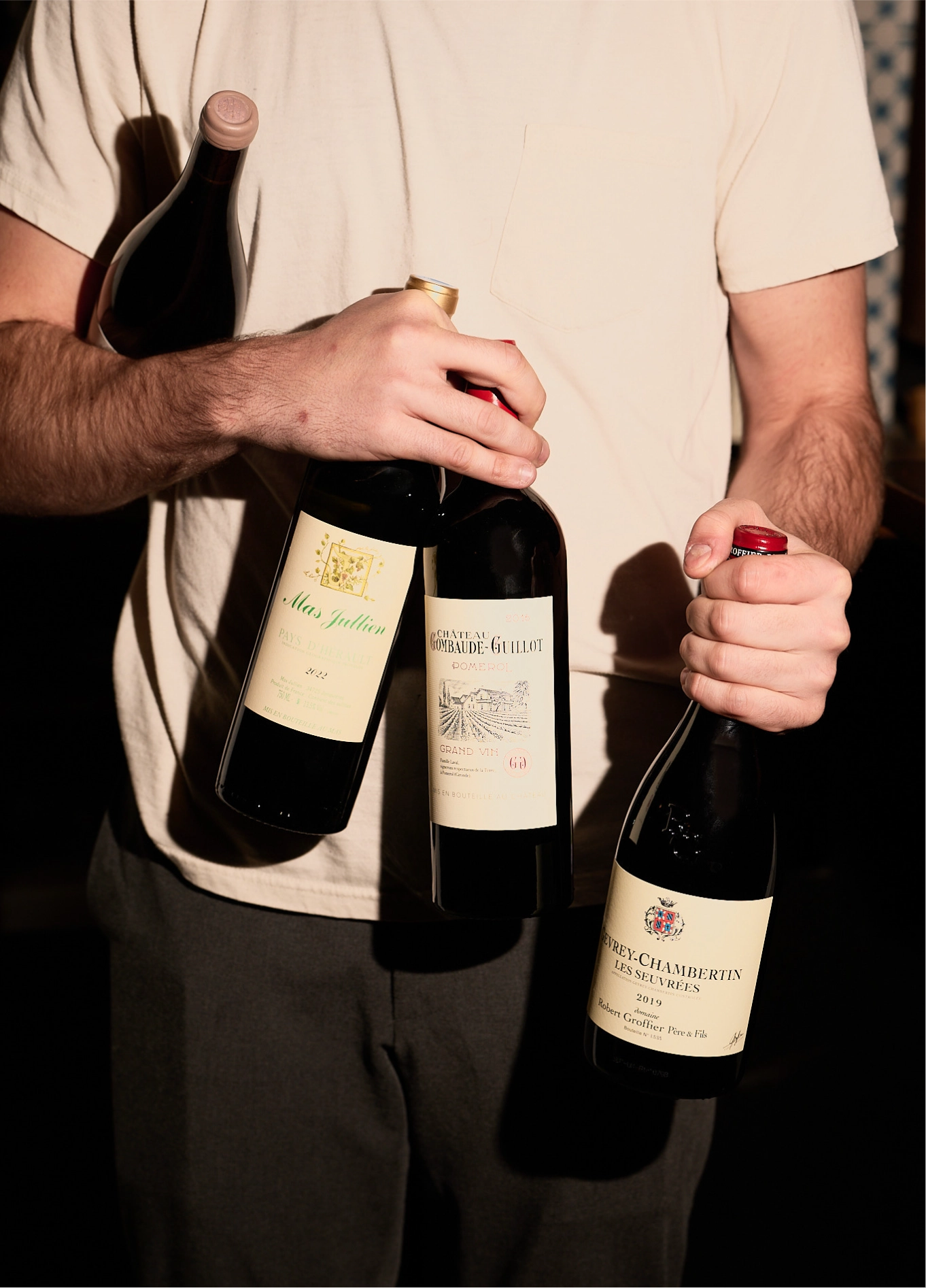 A person holding several bottles of wine at La Compagnie Wine Bar.