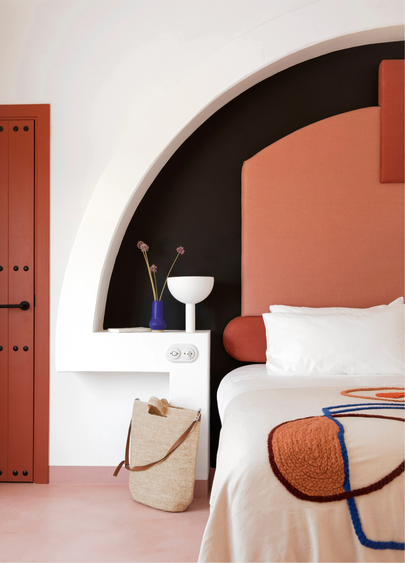 Interior of a room at Menorca Experimental, showcasing an arched alcove, earthy-toned decor, and a warm, minimalist design.