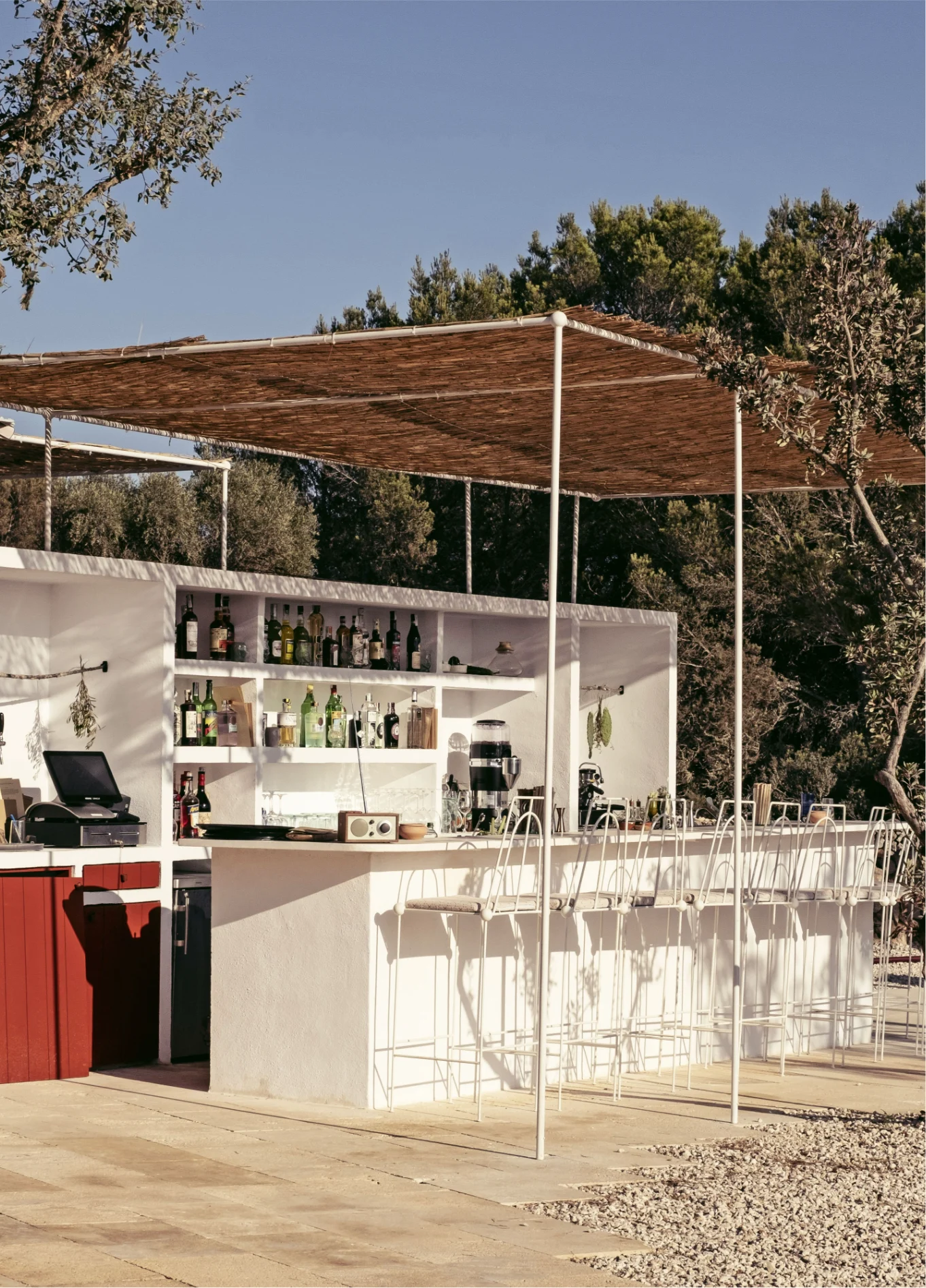 Close-up view of the outdoor setup of a chic beach bar, highlighting its minimalist design and natural shade.
