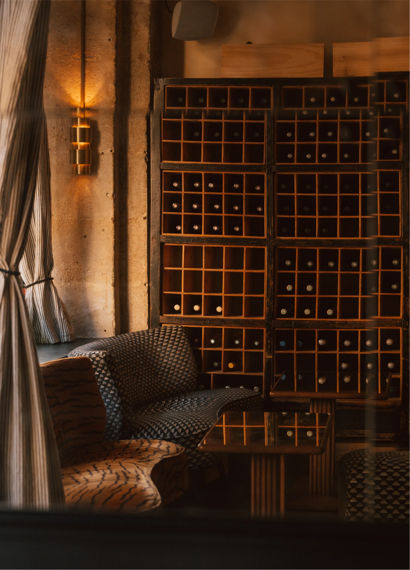 Cozy, dimly lit interior of La Compagnie St Germain featuring a comfortable lounge area and a large wooden wine rack in the background.