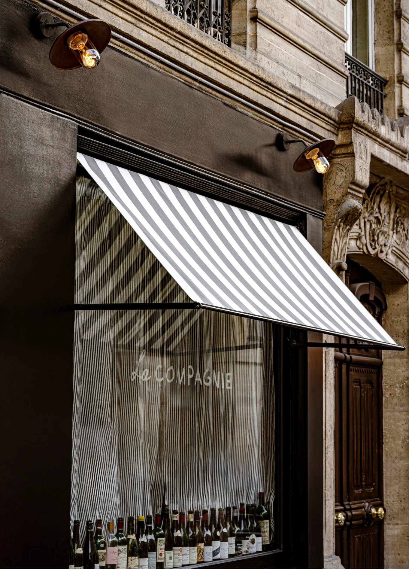 Exterior facade of La Compagnie St Germain featuring a white and gray striped awning over a display window.