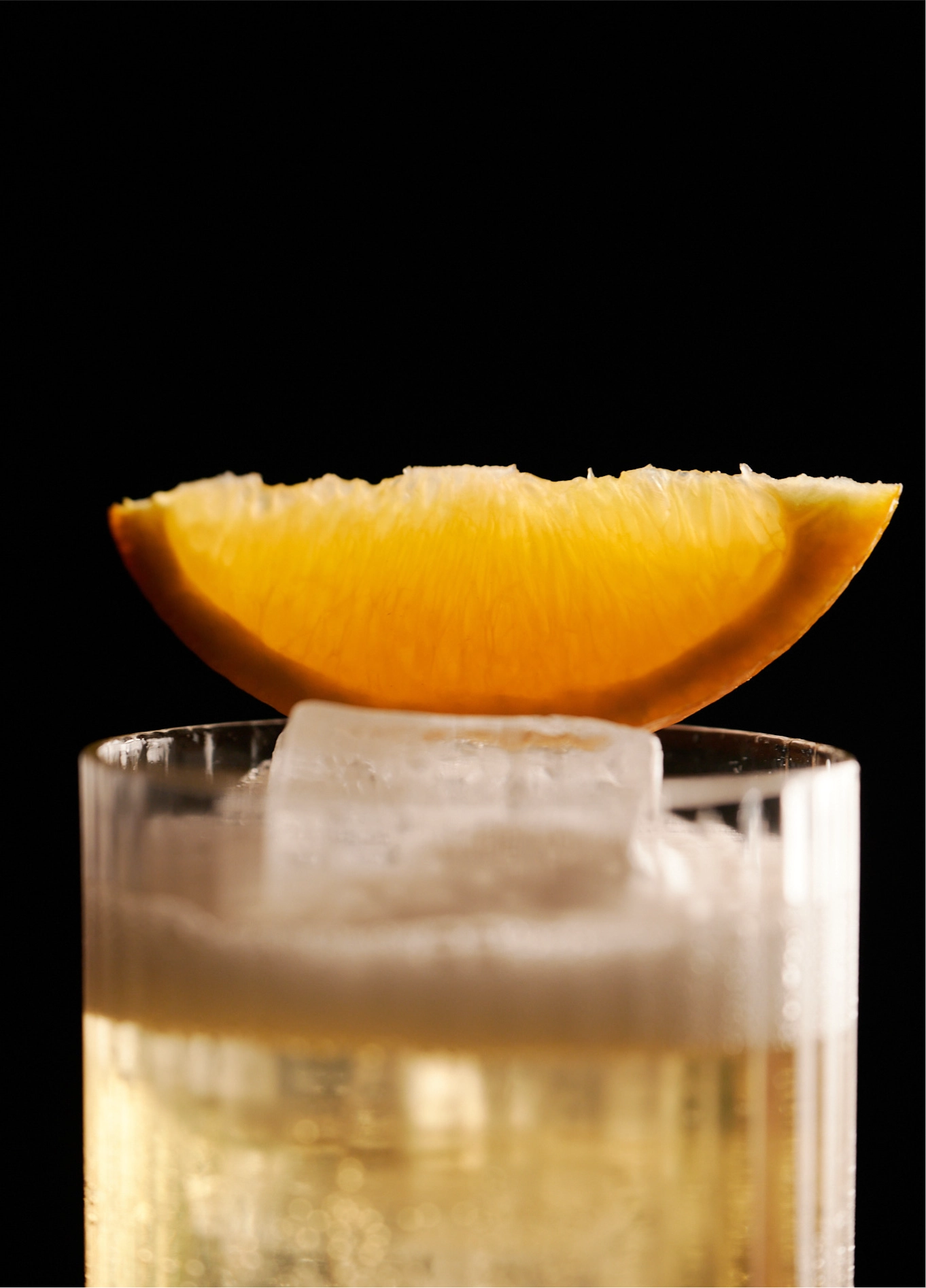 Close-up of a refreshing cocktail with a large ice cube and a citrus slice as a garnish, served at the Experimental Cocktail Club.