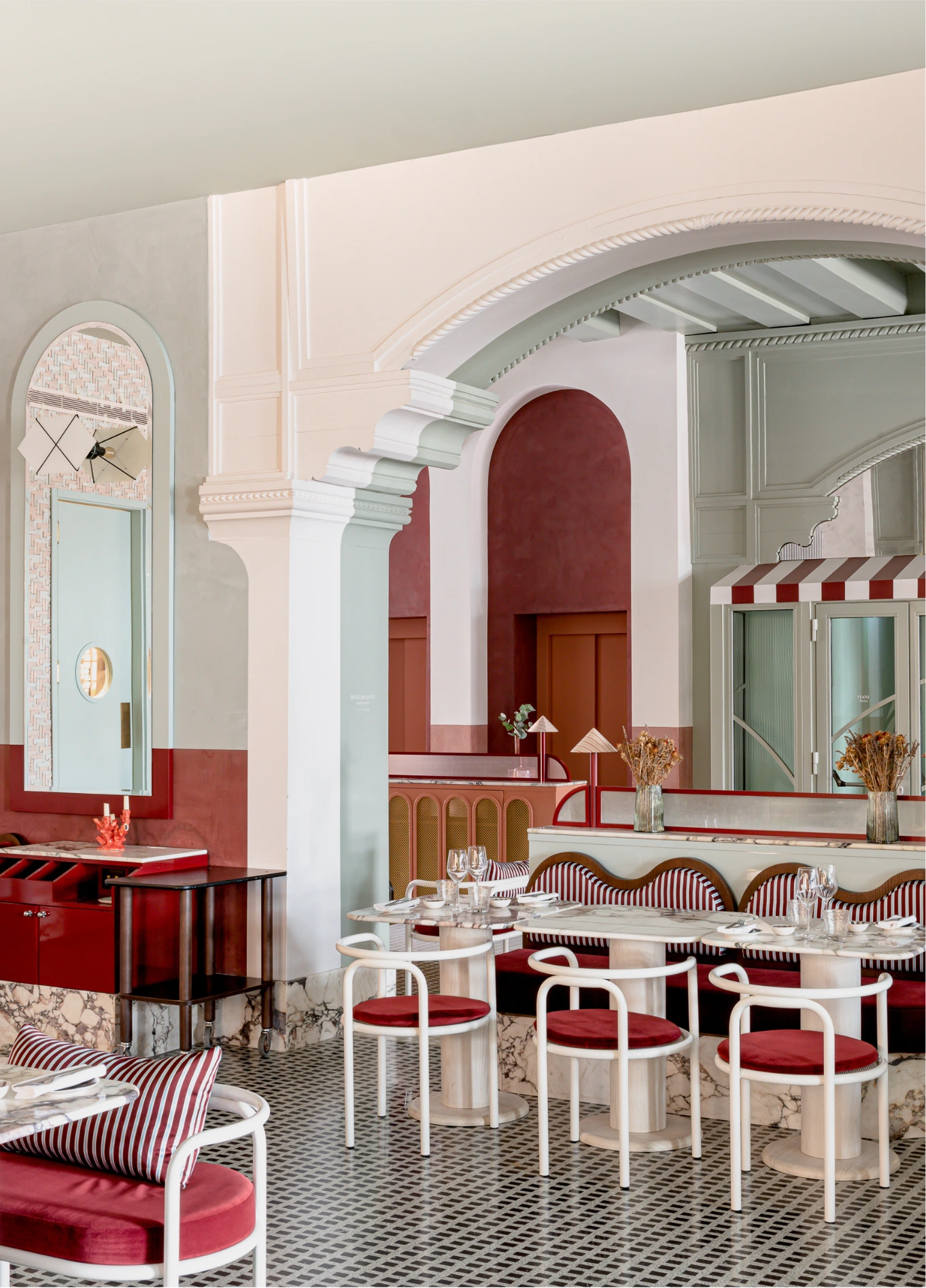 Bright dining room with white arches and red chairs at Adriatica fine dining restaurant, Venice