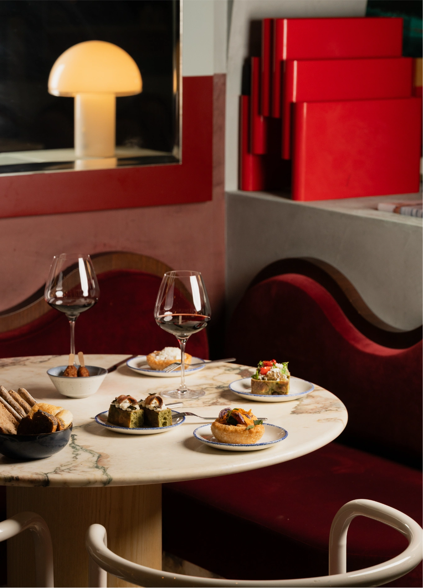 Two gourmet dishes on red banquette at Adriatica upscale restaurant, Venice
