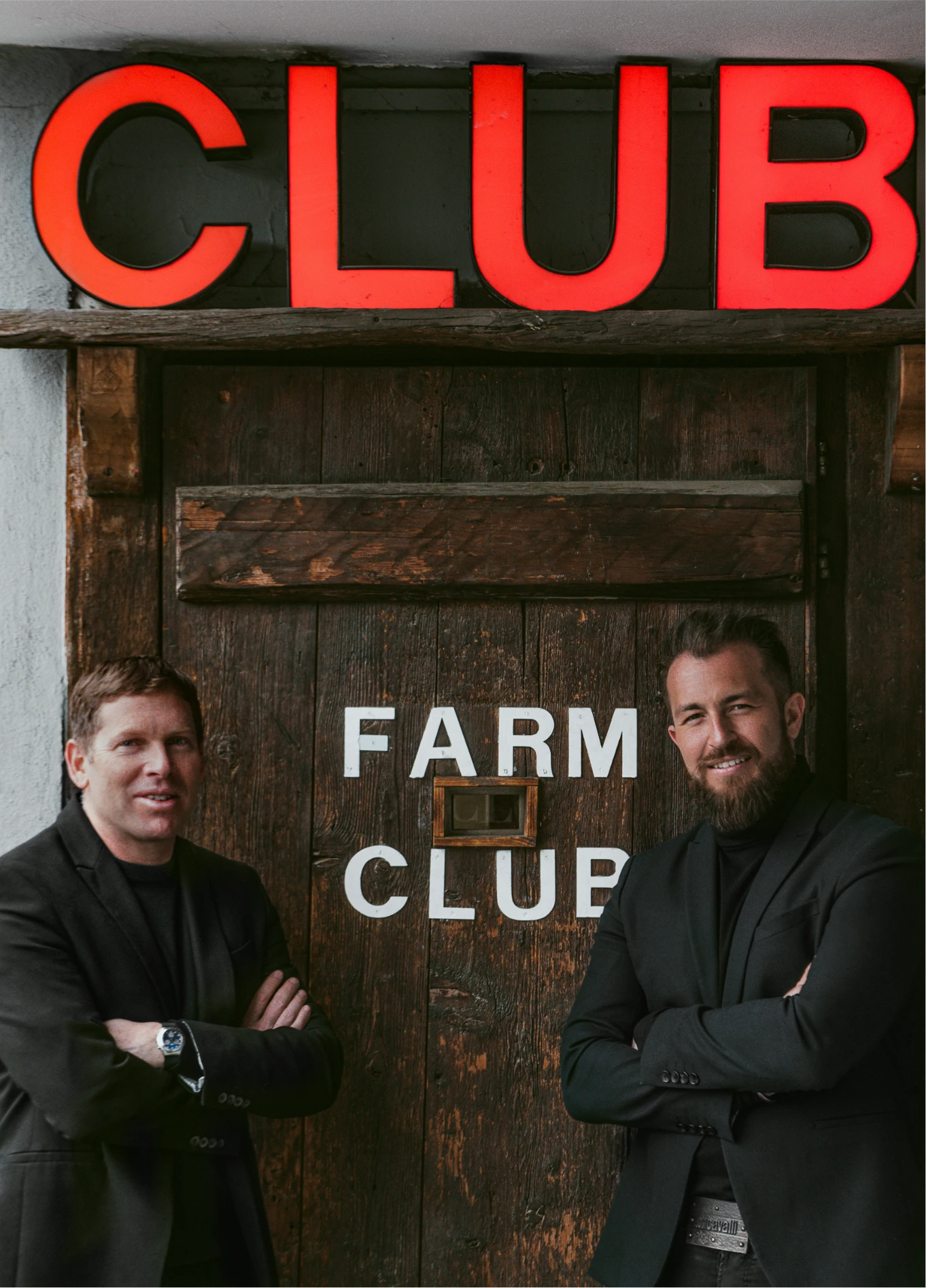 Two men standing in front of Farm Club night club sign, Verbier