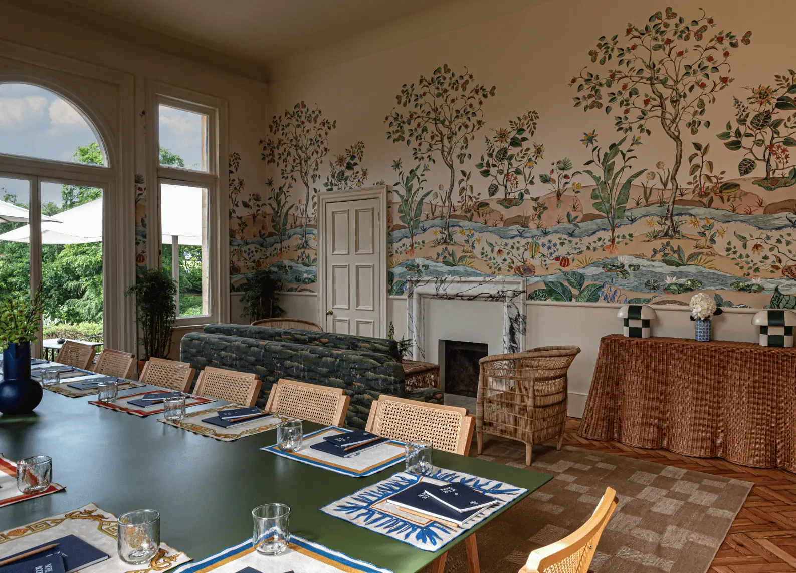Bright room with green table, rattan chairs and botanical wall mural at The Garden Room, Cowley Manor Experimental, Cotswolds