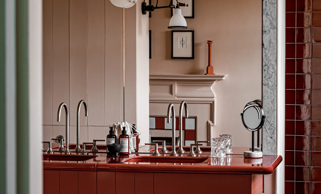 Detail of a dressing area with a red marble countertop, dark wood cabinetry and vintage lighting in the Water Lily room at Cowley Manor Experimental, luxury hotel in the Cotswolds