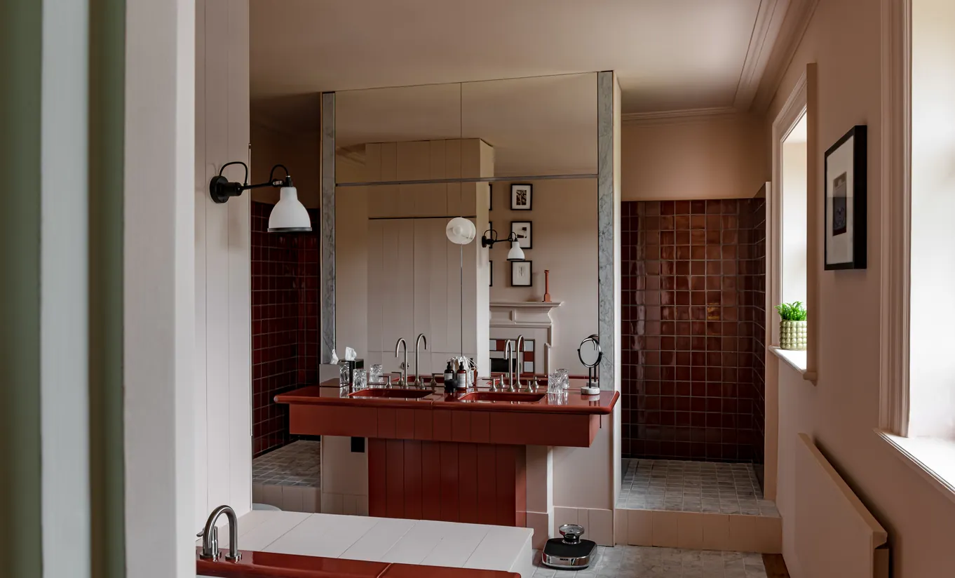 Bathroom with a red marble double sink, dark wood walls and warm lighting in the Water Lily room at Cowley Manor Experimental, luxury spa hotel in the Cotswolds