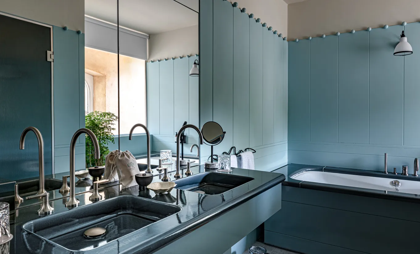 Bathroom with a double sink, teal blue tiles and a large mirror in the Wildflower room at Cowley Manor Experimental, luxury hotel in the Cotswolds