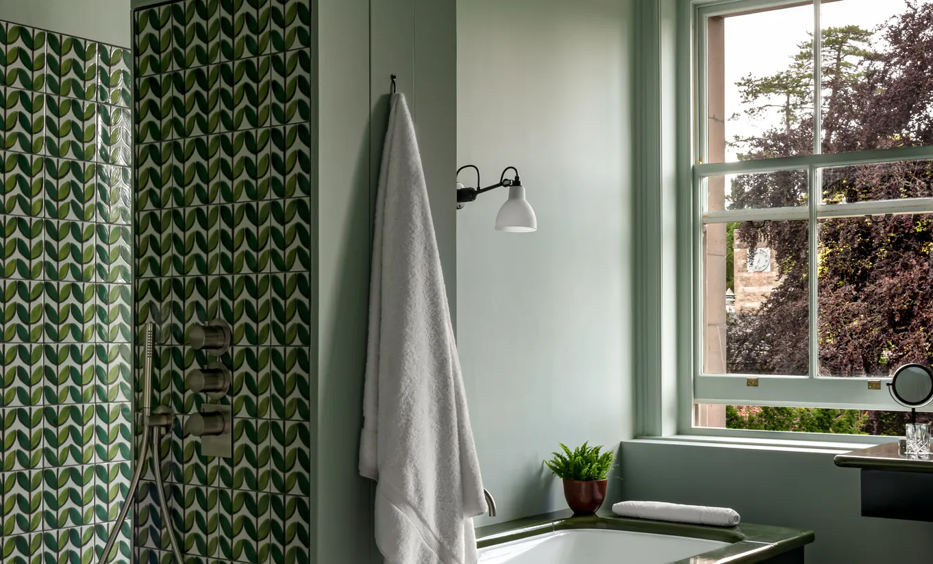 Bathroom with green herringbone tiled walls, a walk-in shower and a view of the garden in the Swan Lake Suite at Cowley Manor Experimental, Cotswolds