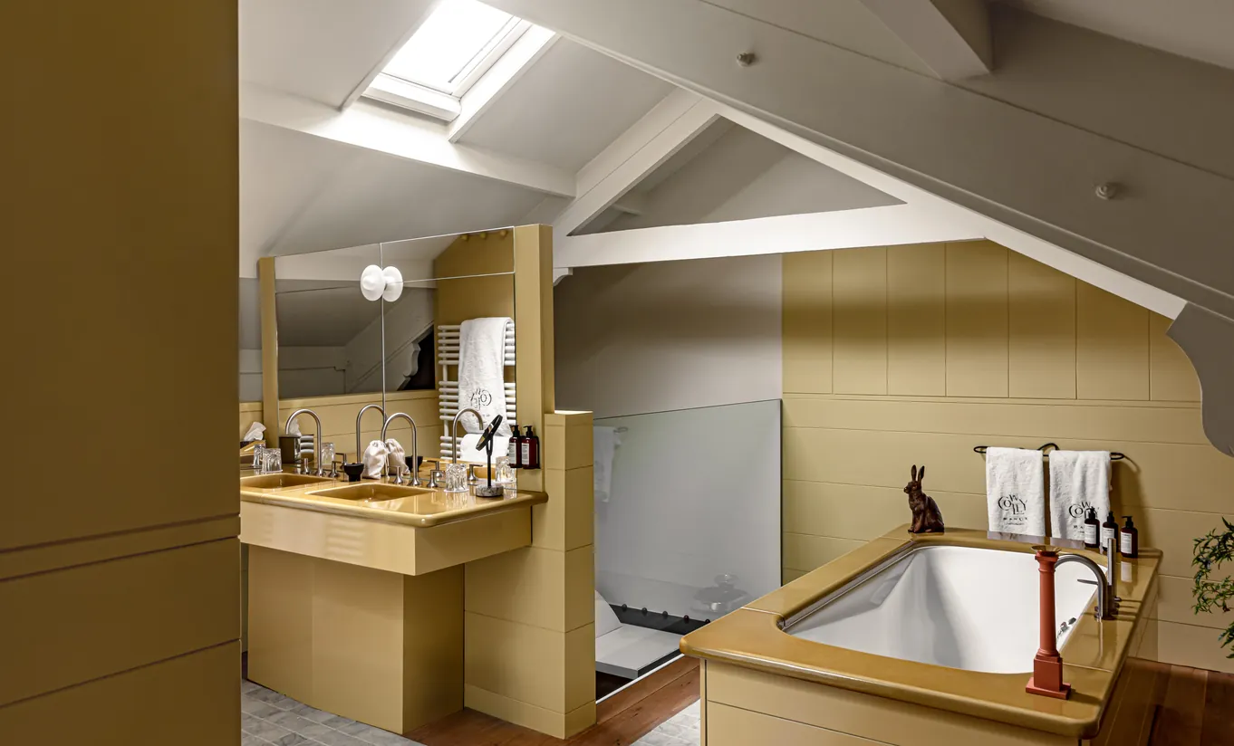 Bathroom with a built-in bathtub, mustard yellow tiles and a skylight in the Wildflower with Terrace room at Cowley Manor Experimental, luxury spa hotel in the Cotswolds