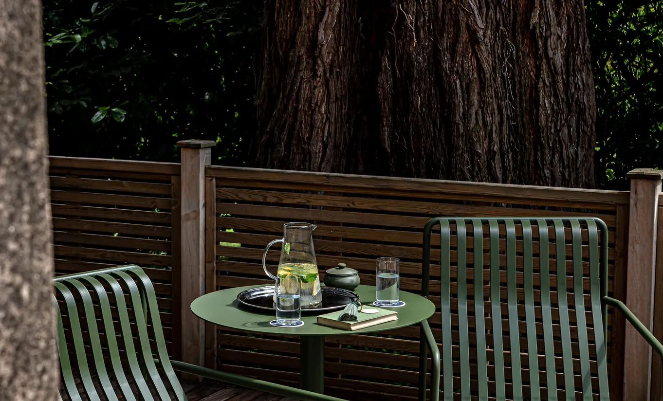 Private wooden terrace with a small table set for drinks surrounded by trees at Cowley Manor Experimental, perfect for a quiet morning in the Cotswolds countryside