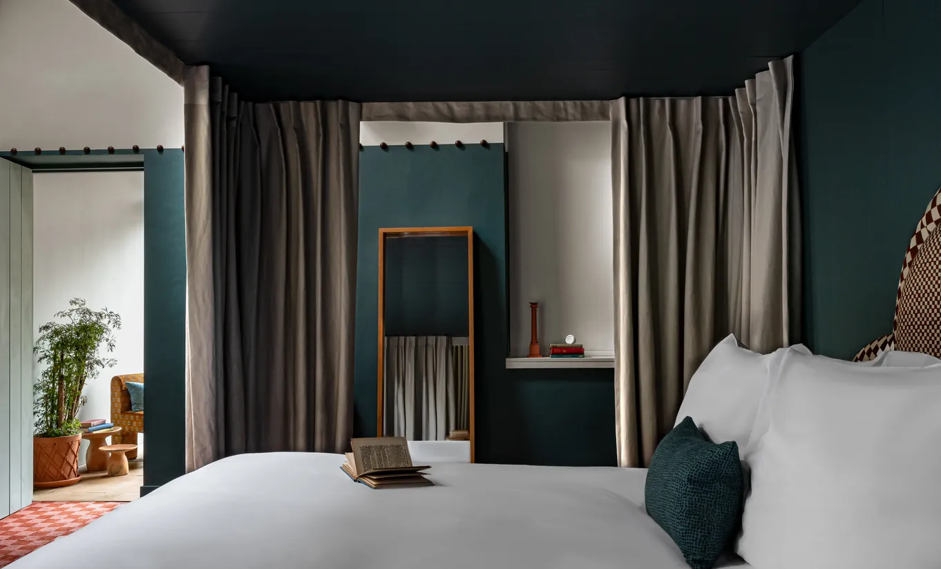 Bedroom with a white double bed, teal blue walls and terracotta pots by the window in the Alpaca's Room at Cowley Manor Experimental, Cotswolds