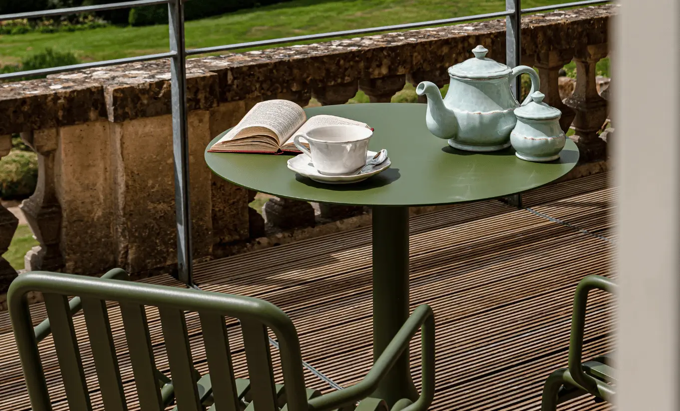 Wooden terrace with garden chairs and a tea set overlooking the green Cotswolds countryside in the St Mary Suite at Cowley Manor Experimental, perfect for a romantic countryside escape