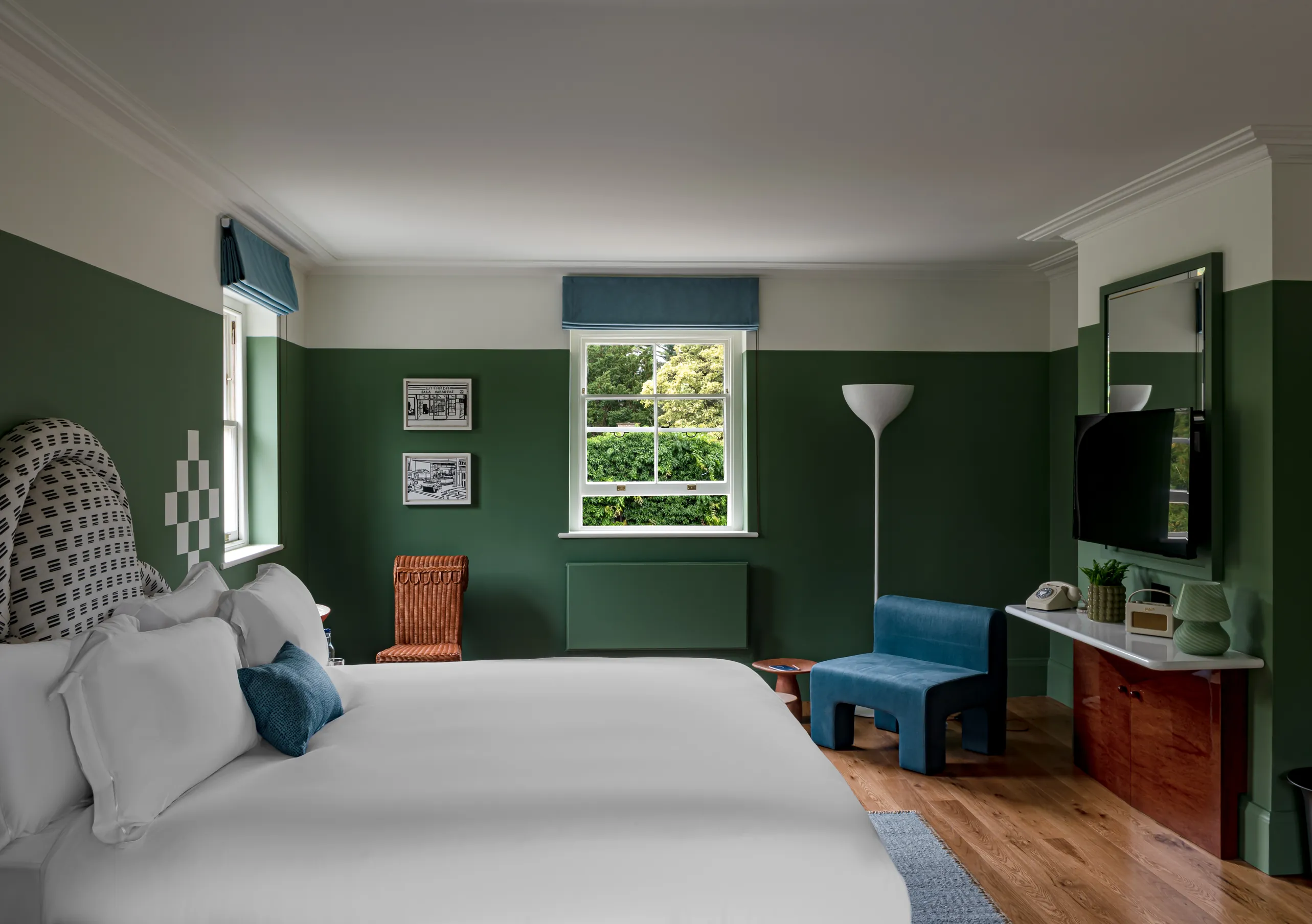 Bedroom with a white double bed, deep green walls and a blue bench at the foot of the bed in the Churns River Junior Suite at Cowley Manor Experimental, Cotswolds.