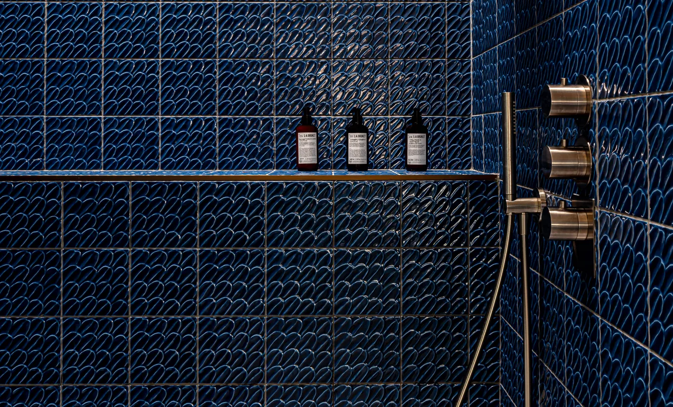 Bathroom with a green built-in bathtub, stone walls and vintage brass taps in the Waterlily with Terrace room at Cowley Manor Experimental, luxury spa hotel in the Cotswolds