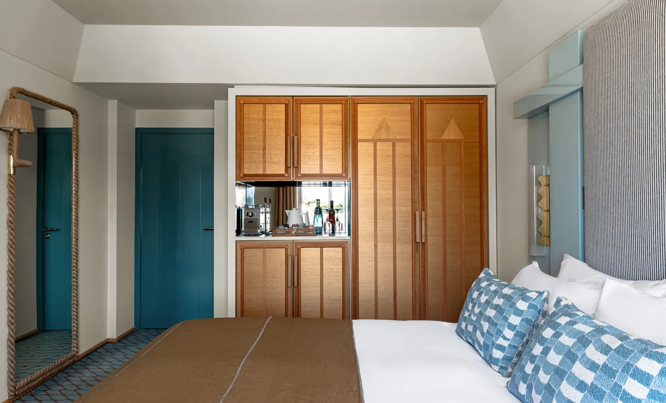 Regina Experimental hotel room with warm wood wardrobe, kitchenette and teal accent door in Venice