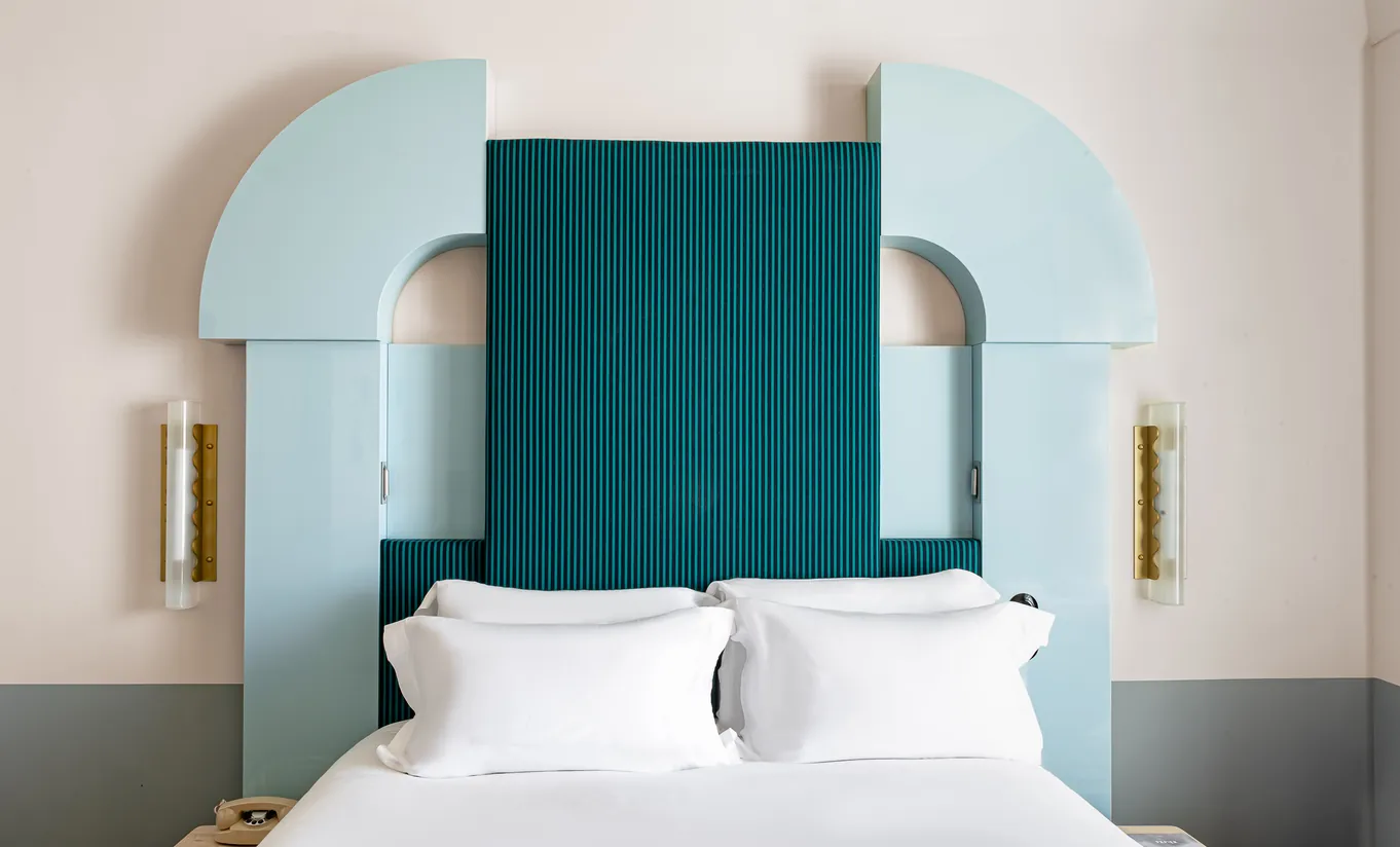 Regina Experimental hotel bedroom with bold teal velvet headboard and white arched alcoves in Venice