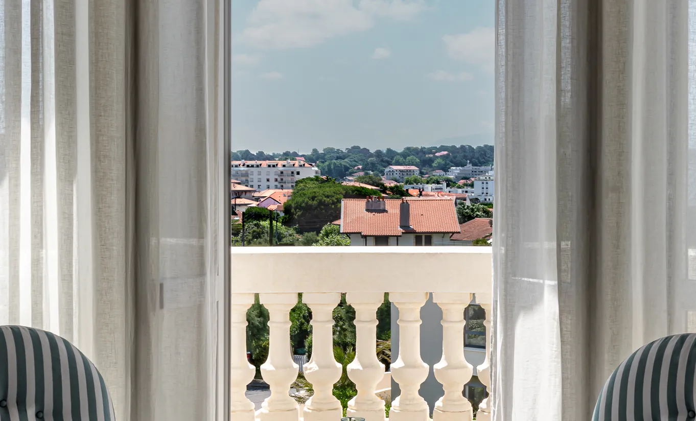 Experimental Group Rome hotel suite with elegant armchairs and wraparound balcony showcasing panoramic city rooftop views