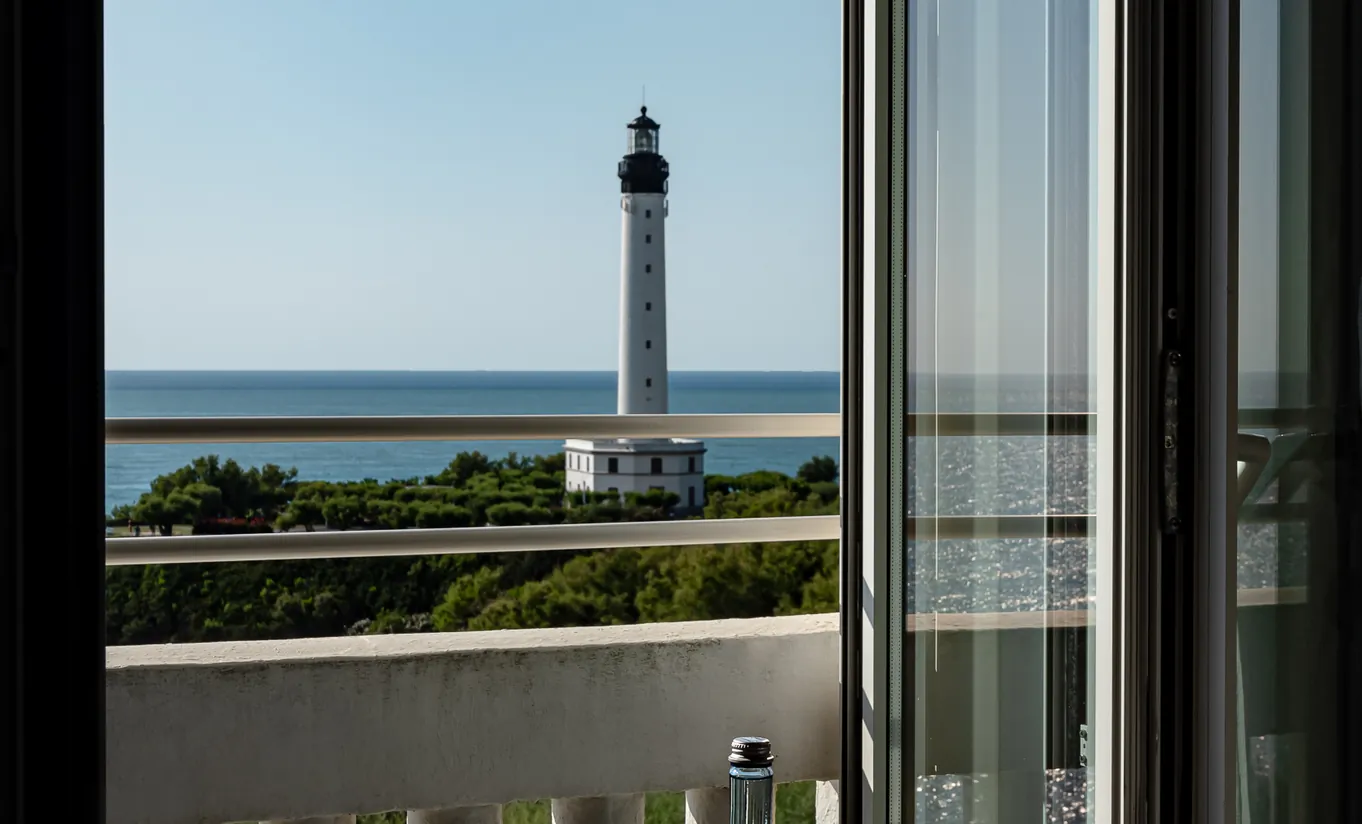 Regina Experimental hotel room window view of Biarritz lighthouse and Atlantic Ocean coastline on a clear day