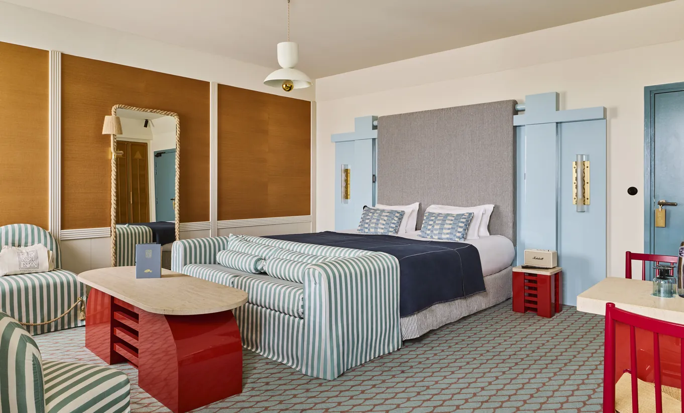 Regina Experimental hotel deluxe room with upholstered headboard, coral wall panel and red accent furniture