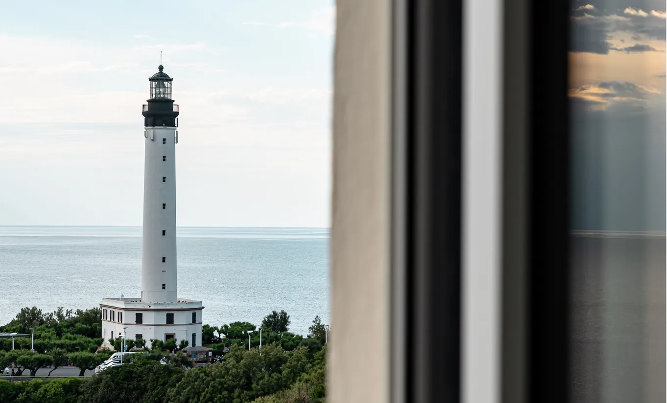 Regina Experimental Biarritz hotel room window with close-up view of the iconic Biarritz lighthouse surrounded by green trees