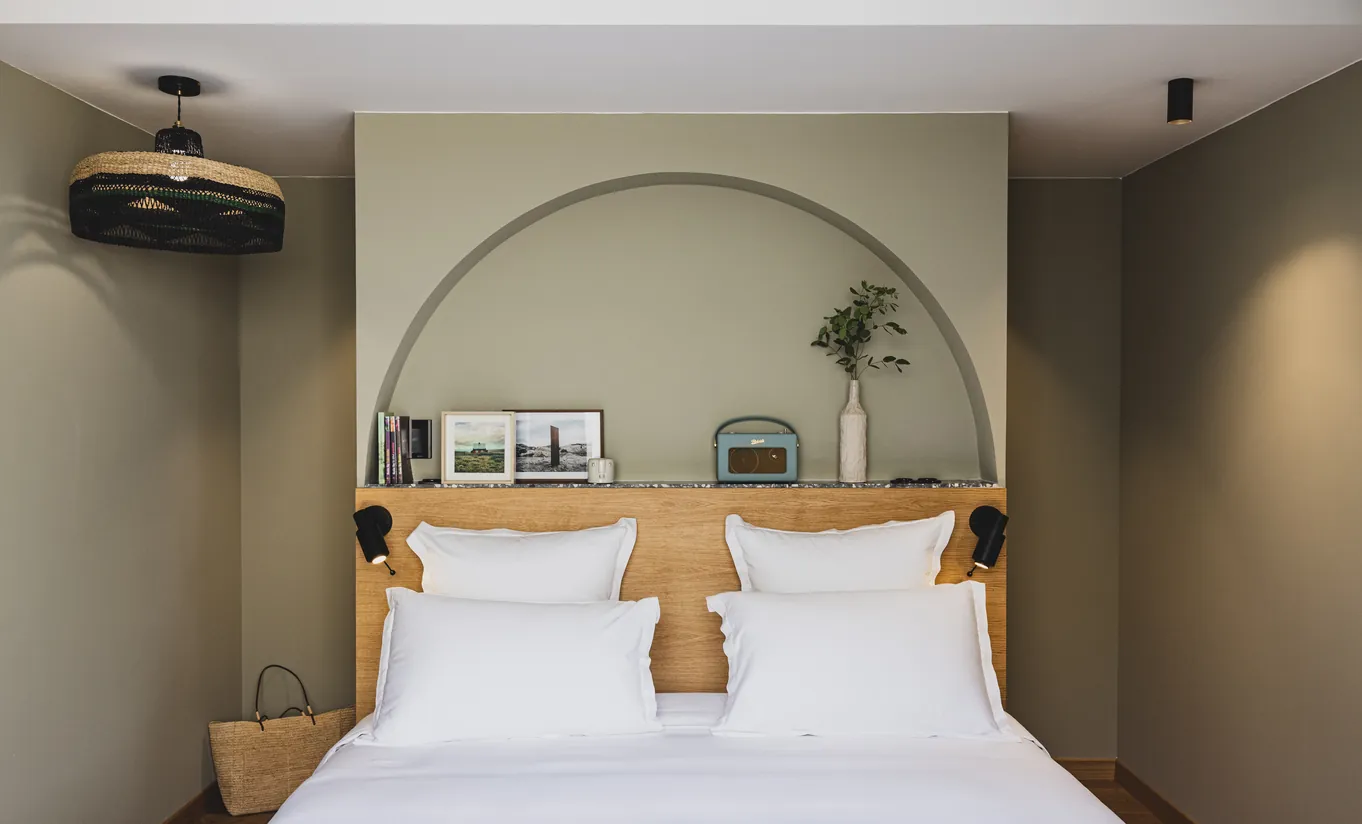 Experimental Group hotel elegant double bedroom featuring arched headboard wall detail and warm neutral tones