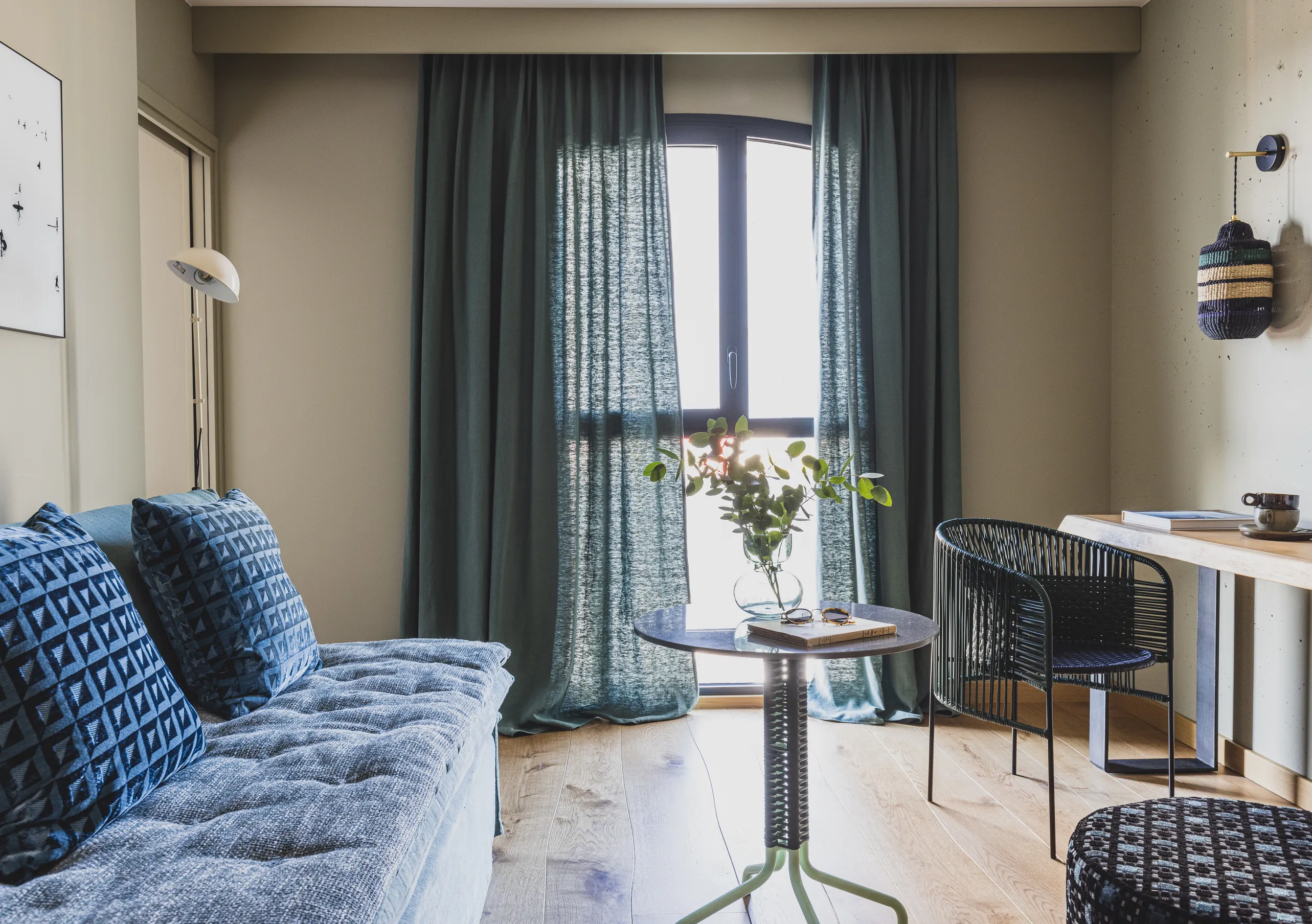 Experimental Group hotel modern living room with blue sofa and floor-to-ceiling curtains.