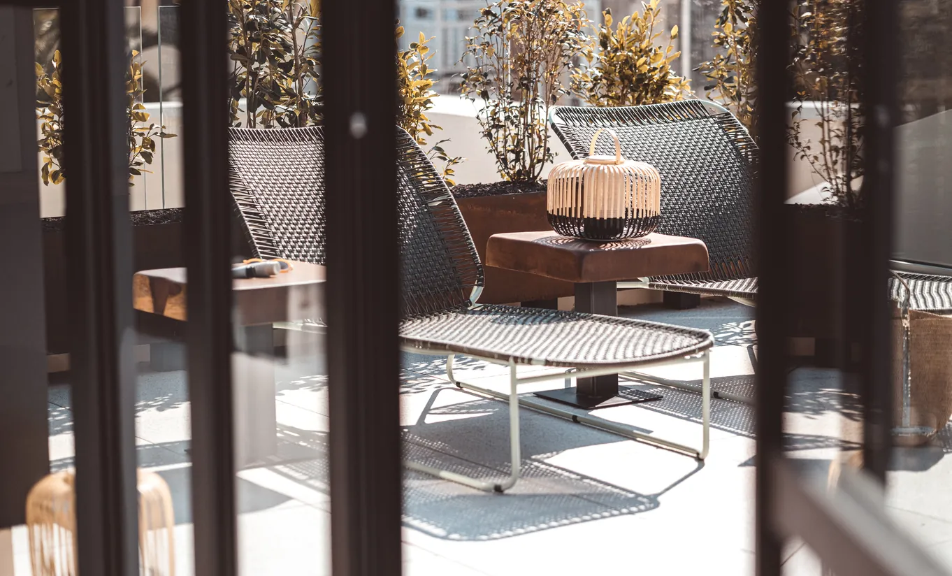 Experimental Group hotel private outdoor terrace with wooden lounge chairs and lush garden surroundings