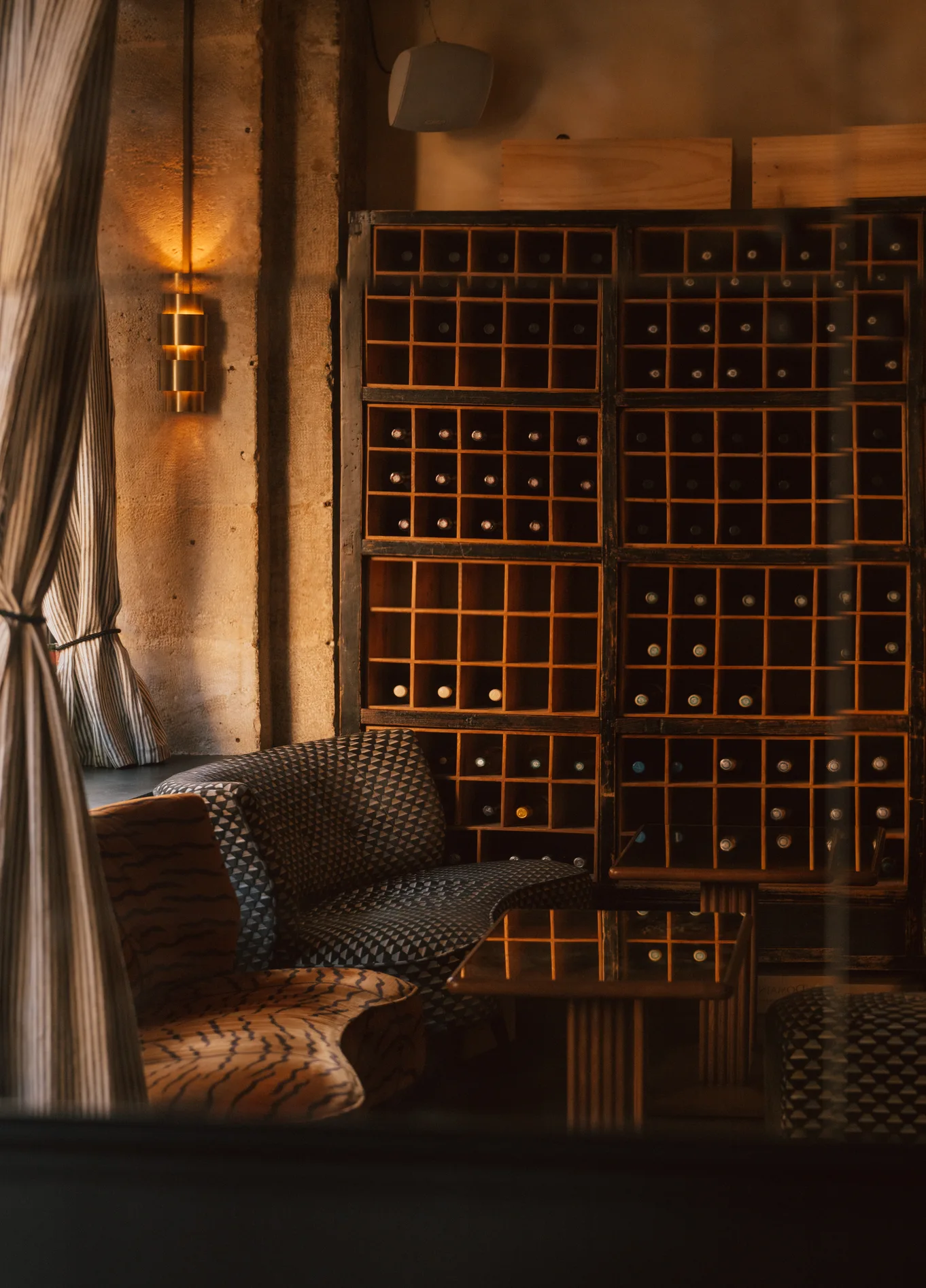 Cozy, dimly lit interior of La Compagnie St Germain featuring a comfortable lounge area and a large wooden wine rack in the background.