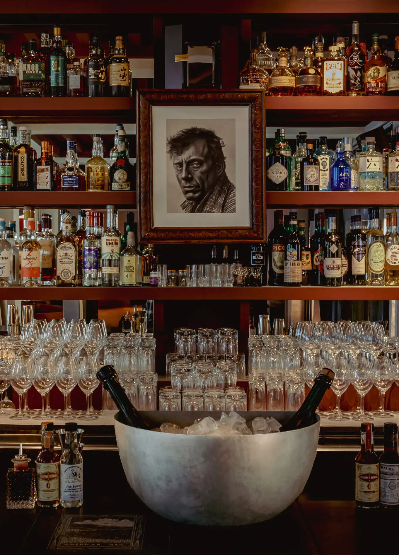 Wall of bottles with portrait and ice bucket at American Bar, Experimental Marais, Paris